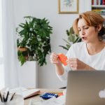 Mulher revisa contas em uma mesa com laptop, organizando as finanças pessoais em casa.
