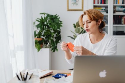 Mulher revisa contas em uma mesa com laptop, organizando as finanças pessoais em casa.