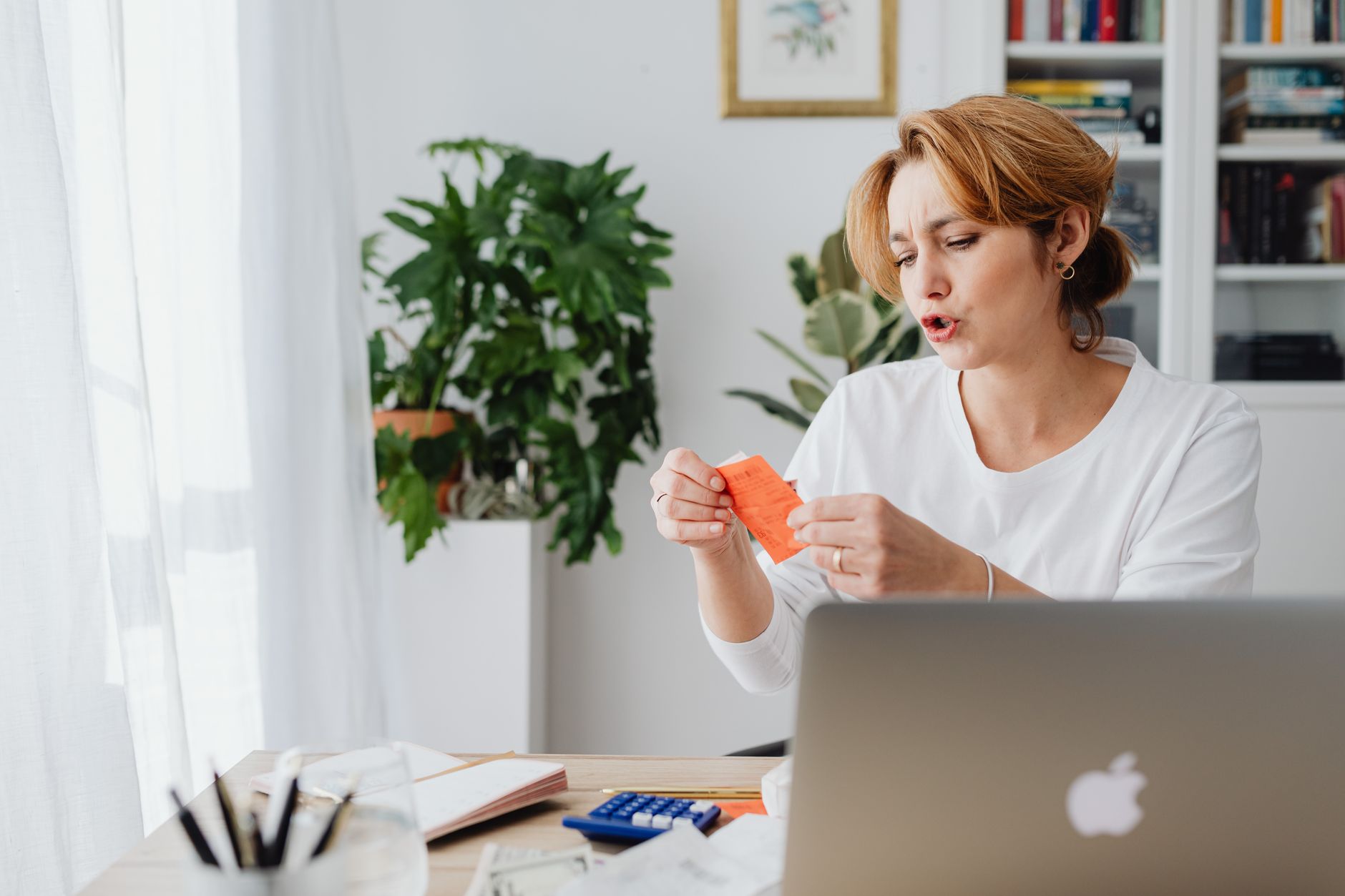 Mulher revisa contas em uma mesa com laptop, organizando as finanças pessoais em casa.