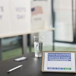 Tablet exibe uma tela de cadastro eleitoral em uma seção de votação interna, com sinalização relacionada ao dia da eleição.