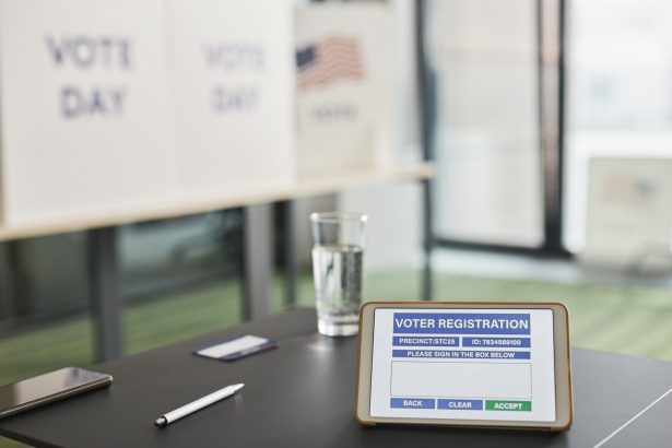 Tablet exibe uma tela de cadastro eleitoral em uma seção de votação interna, com sinalização relacionada ao dia da eleição.