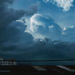 Nuvens carregadas se formando sobre telhados de uma área urbana durante uma tempestade