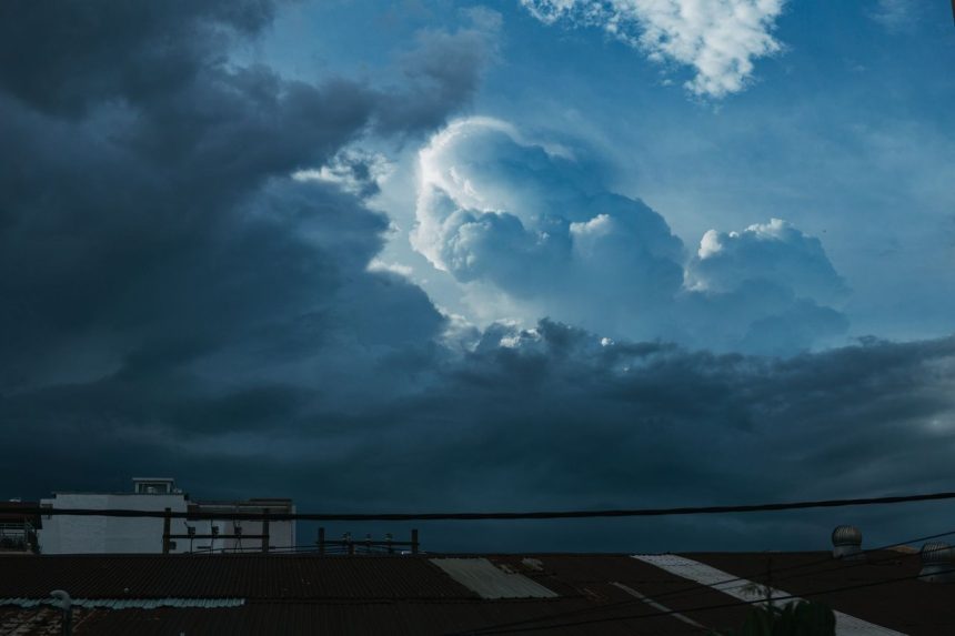 Nuvens carregadas se formando sobre telhados de uma área urbana durante uma tempestade