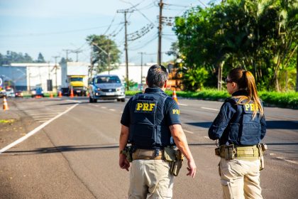 Agentes da Polícia Rodoviária Federal monitoram o trânsito em uma via durante o dia.