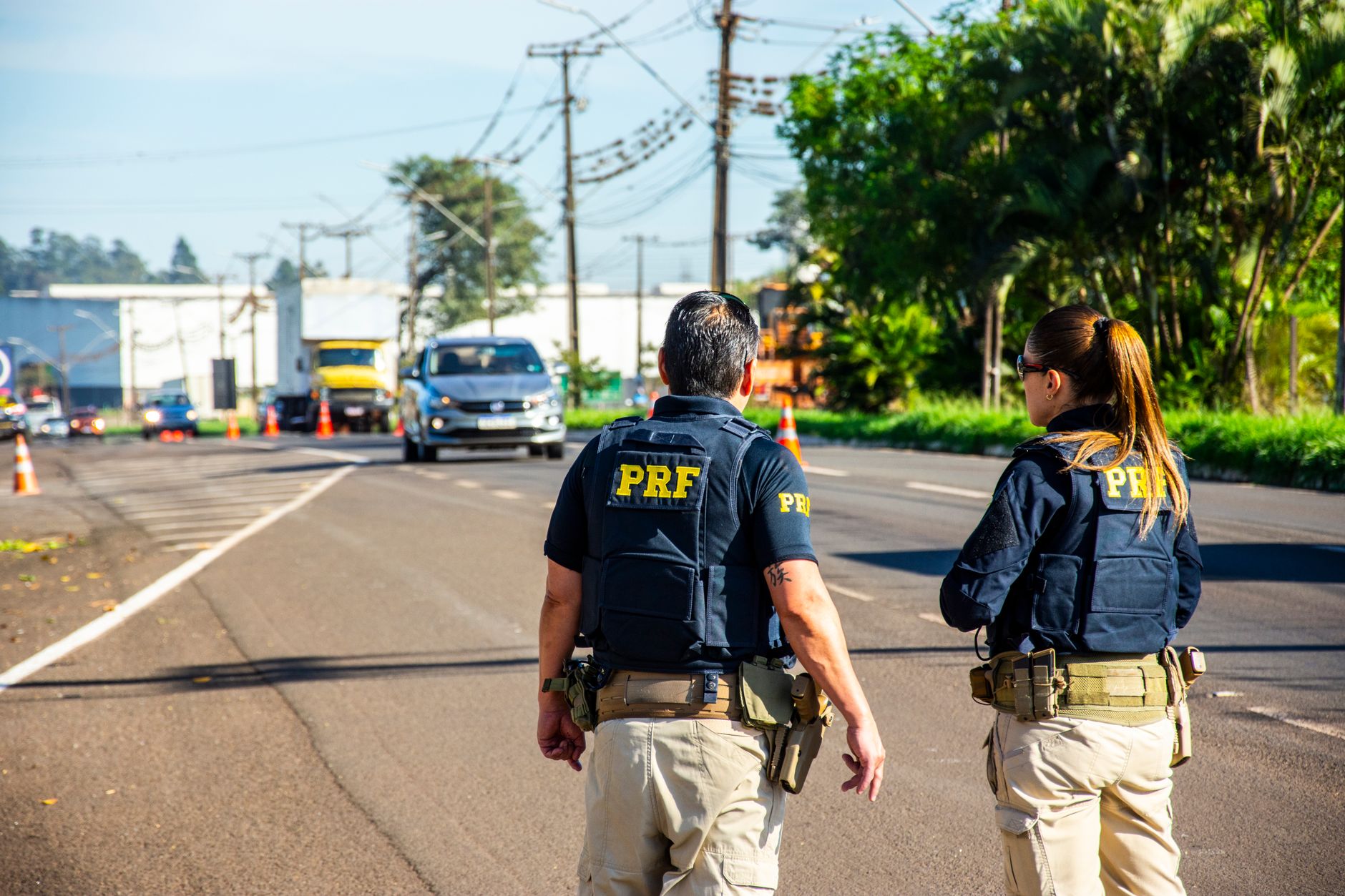 Agentes da Polícia Rodoviária Federal monitoram o trânsito em uma via durante o dia.