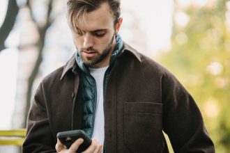 Homem recebe uma mensagem no celular enquanto está em uma rua.