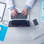 Computador portátil sobre uma mesa de trabalho associada à gestão de serviços de saúde