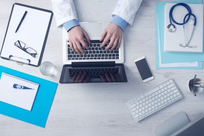 Computador portátil sobre uma mesa de trabalho associada à gestão de serviços de saúde