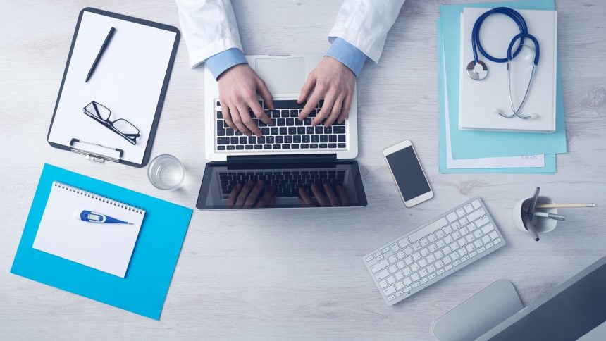 Computador portátil sobre uma mesa de trabalho associada à gestão de serviços de saúde